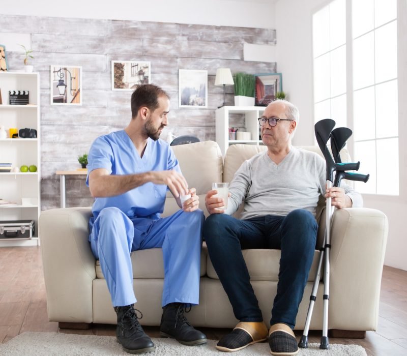 young-male-nurse-in-nursing-home-with-pills-for-senior-man.jpg